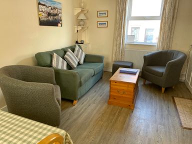 A living room with a sofa and armchairs at Guinea Cottage in Brewers Quay Harbour