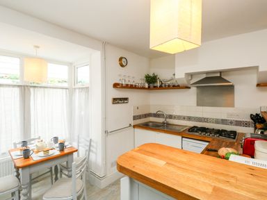 A kitchen with wooden countertops and a small dining table set with cups and plates at Harbour Catch Cottage in Weymouth