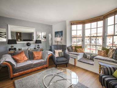 A living room with a sofa chair bay window seating and a glass coffee table at Harbourside House in Brewers Quay Harbour
