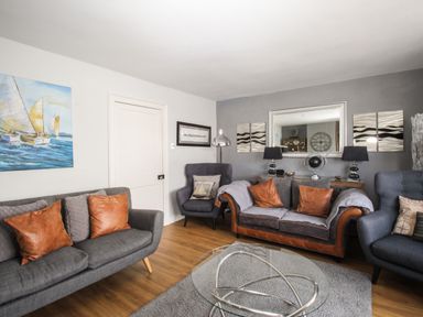 A living room with sofas chairs artwork and a glass coffee table at Harbourside House in Brewers Quay Harbour