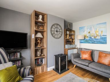 A living room with a wall clock a television and a grey sofa at Harbourside House Brewers Quay Harbour