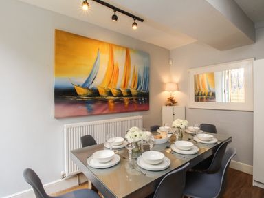 A dining room with a glass table set for six people with white dishes and glasses at Harbourside House Brewers Quay Harbour