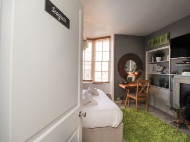 A bedroom with a bed desk chair round mirror green rug and built in shelves at Harbourside House in Brewers Quay Harbour
