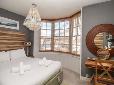 A bedroom with a bed with rolled towels a chandelier a wooden desk and a round mirror at Harbourside House Brewers Quay Harbour