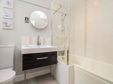 A bathroom with a toilet sink mirror and bathtub with shower at Harbourside House in Brewers Quay Harbour