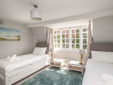 A bedroom with two single beds nightstands and lamps and a large window at Harbourside House in Brewers Quay Harbour