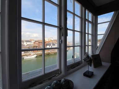 A window view over a harbor with boats and buildings at Harbourside House Brewers Quay Harbour