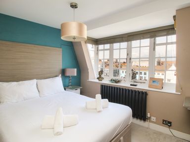 A bedroom with a bed and rolled towels near a window with decorative items at Harbourside House in Brewers Quay Harbour