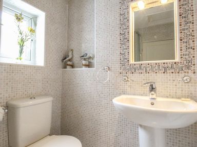 A bathroom with a toilet a sink above sink mirror and window with flowers at Harbourside House in Brewers Quay Harbour