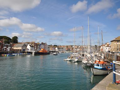 A harbour with boats docked along the quay and buildings lining the waterfront at Harbourside House in Brewers Quay Harbour