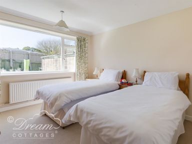 A bedroom with two single beds bedside tables and lamps at Hillview Bungalow in Burton Bradstock