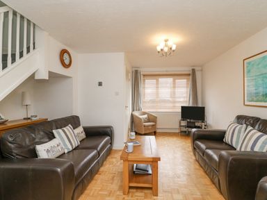 A living room with two dark sofas a wooden coffee table and a small television at Home Waters in Wyke Regis