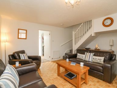 A living room with leather sofas wooden coffee table and staircase at Home Waters in Wyke Regis