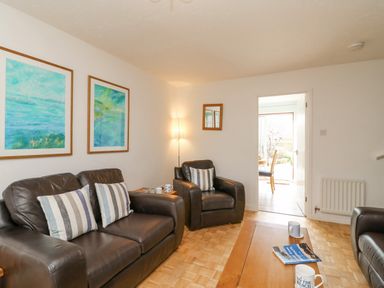 A living room with dark leather sofas striped pillows wooden table and paintings at Home Waters in Wyke Regis