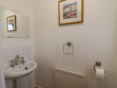 A small bathroom with a sink towel holder radiator toilet paper holder and a framed picture on the wall at Home Waters in Wyke Regis