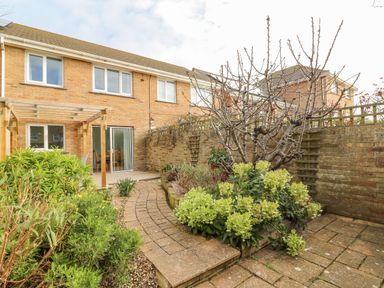 A backyard with brick paving a wooden pergola and various plants at Home Waters in Wyke Regis