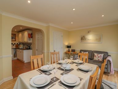 A dining area with a set table and wooden chairs next to a living space with a sofa and a small round table at Hops House Brewers Quay Harbour