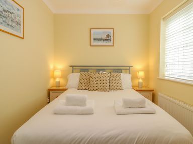 A bedroom with a double bed with pillows and folded towels bedside lamps on tables and framed pictures on walls at Hops House in Brewers Quay Harbour