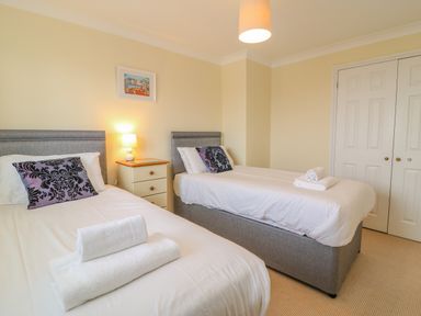 A bedroom with two single beds each with white linens and folded towels bedside table with lamp and a framed picture on the wall at Hops House in Brewers Quay Harbour
