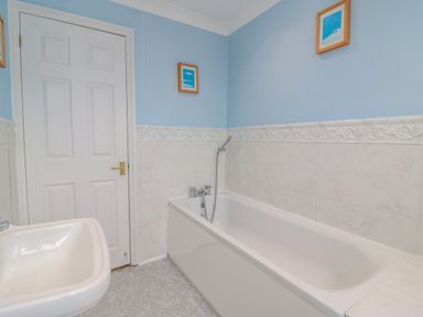 A bathroom with a bathtub a sink a closed door and two framed pictures on blue and white tiled walls at Hops House Brewers Quay Harbour