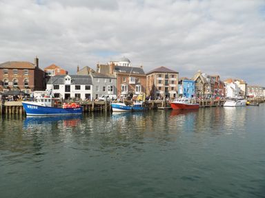 A harbor with boats docked alongside buildings and a waterfront promenade at Hops House in Brewers Quay Harbour