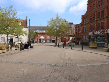 A paved town square with benches trees and buildings including Brewers Quay at Brewers Quay Harbour