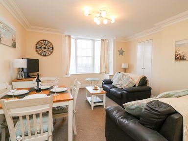 A living room with a dining table set for four a television and two leather sofas at Harbour Watch Apartment 1 Brewers Quay Harbour