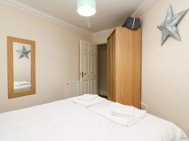 A bedroom with a bed, wardrobe, wall mirror, and star decoration at Harbour Watch Apartment 1 in Brewers Quay Harbour