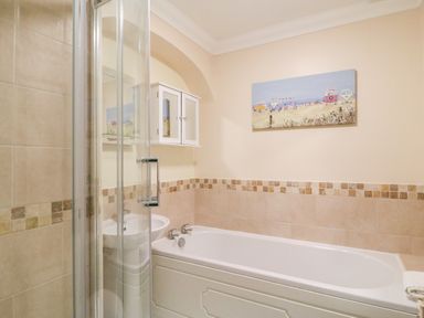 A bathroom with a bathtub shower sink mirror cabinet and a painting at Harbour Watch Apartment 1 Brewers Quay Harbour