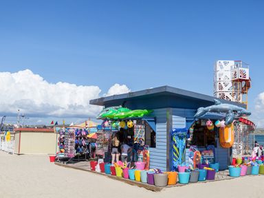 An outdoor beach shop selling inflatable toys buckets and swimwear on a sandy beach at Brewers Quay Harbour