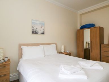 A bedroom with a bed with white linens two bedside tables with lamps and a wardrobe with a mirror at Harbour Watch Apartment 6 Brewers Quay Harbour