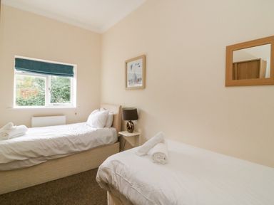 A bedroom with two single beds with rolled towels on them and a window with a blue blind at Harbour Watch Apartment 6 Brewers Quay Harbour
