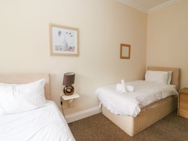 A bedroom with two single beds a nightstand lamp and wall art at Harbour Watch Apartment 6 Brewers Quay Harbour