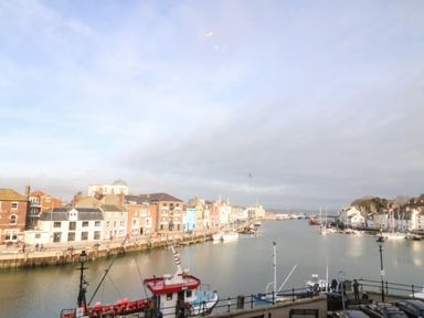 A harbor with boats docked along a waterfront lined with buildings at Harbour Watch Apartment 6 Brewers Quay Harbour