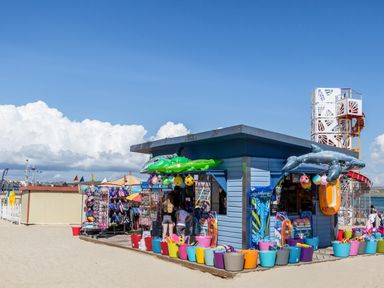 A beachside stall selling inflatable toys and beach accessories with a playground structure in the background at Harbour Watch Apartment 6 Brewers Quay Harbour