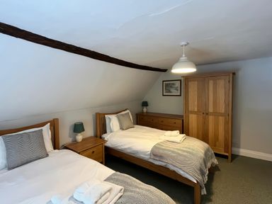 A bedroom with two beds and a wardrobe at Ivy Cottage in West Lulworth