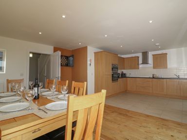 A kitchen with wooden cabinets and a dining table set with plates and glasses at Jurassic Coast House in Portland