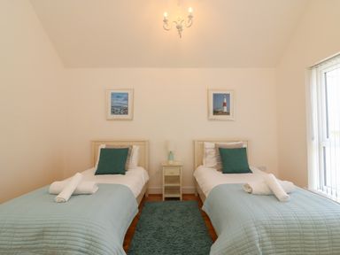 A bedroom with two single beds bedside table lamp and pictures on the wall at Jurassic Coast House in Portland