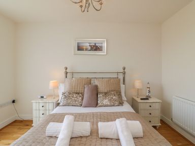 A bedroom with a bed with pillows and towels and two bedside tables with lamps at Jurassic Coast House in Portland
