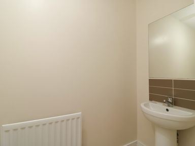 A bathroom with a white sink pedestal and a mirror above it alongside a white radiator on the wall Jurassic Coast House Portland