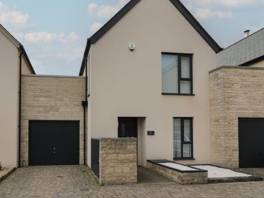 A modern house with a black garage door and two windows at Jurassic Coast House in Portland