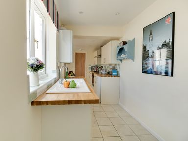 A kitchen with wooden countertops a white sink vegetables on the counter and a framed picture on the wall at Langham Cottage in Portland