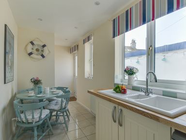 A kitchen with a dining table and chairs and a sink with vegetables on the counter at Langham Cottage in Portland