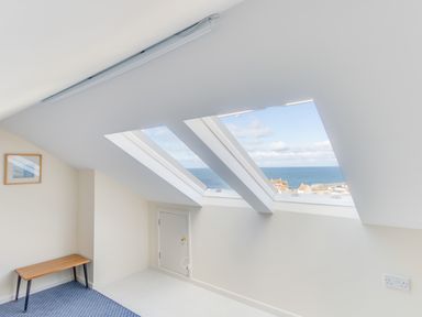 An attic room with two skylight windows a small door a bench and a framed picture at Langham Cottage in Portland