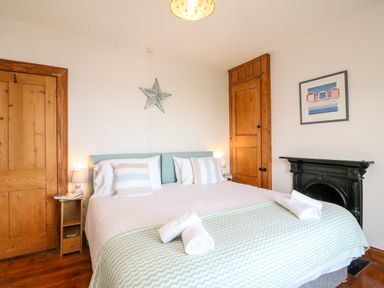 A bedroom with a bed with striped pillows and folded towels near wooden doors at Langham Cottage in Portland