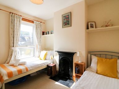 A bedroom with two single beds a black fireplace and a window with curtains at Langham Cottage in Portland