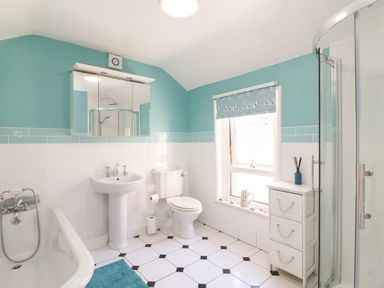 A bathroom with bathtub sink toilet shower and storage unit at Langham Cottage in Portland