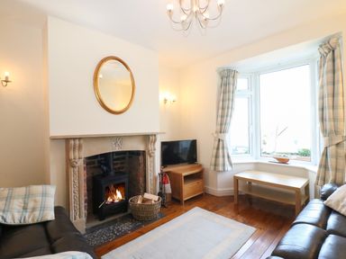 A living room with a fireplace a round mirror above and two leather sofas at Langham Cottage in Portland