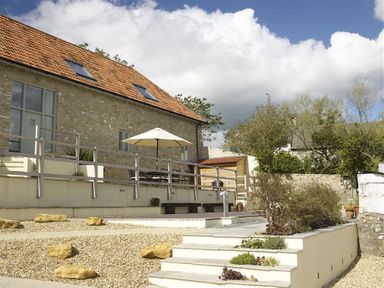 An outdoor patio area with a stone building roof and stairs with plants at Leys At Valley View Farm in Uplyme