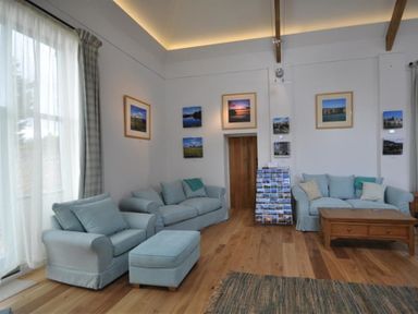 A sitting room with two sofas an armchair and ottoman a wooden coffee table photographs on walls at Leys At Valley View Farm in Uplyme